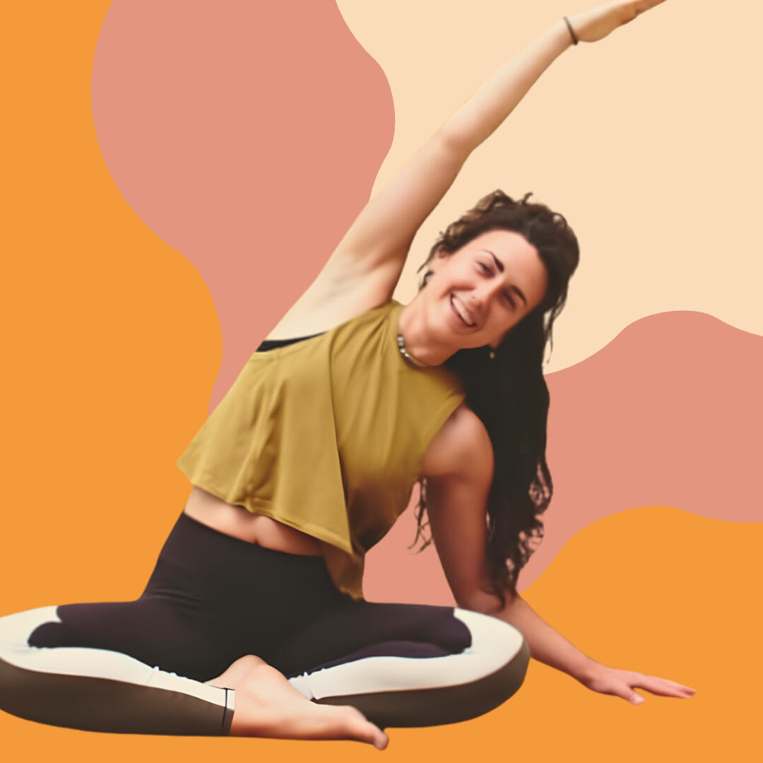 Yoga photo 1 A photo of Liv smiling in a yoga posture. She is sitting with her legs crossed, her left hand resting on the floor and she is reaching her right arm over her head. There is an orange, pink and peach background.